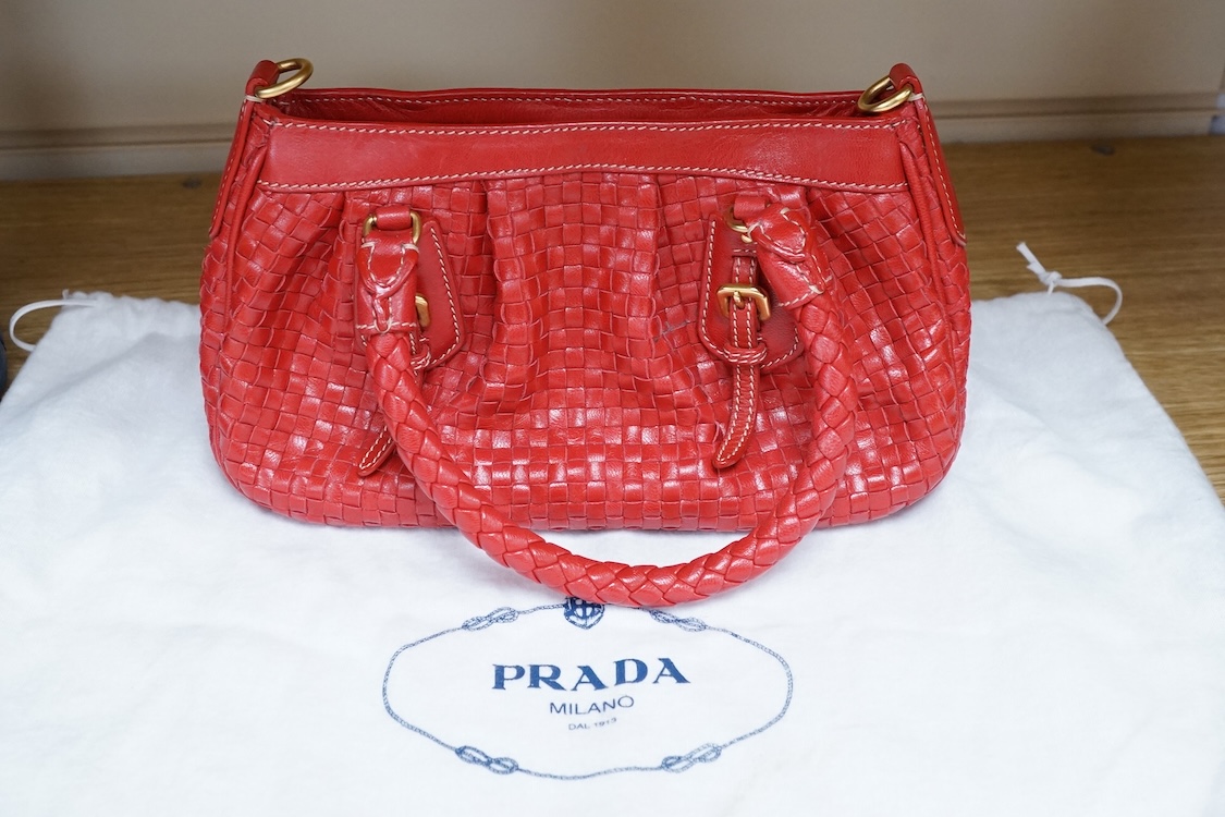 A Prada red braided leather handbag with shoulder strap, authenticity card and dust cover, 25cm wide, Provenance: Purchased by the vendor in Selfridges